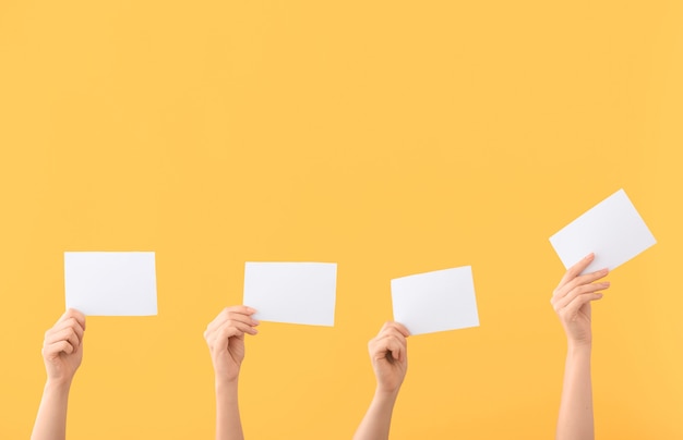 Mains de personnes votantes avec des bulletins de vote sur la couleur