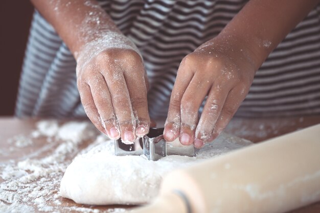 Les mains de petite fille enfant prépare une pâte pour faire cuire des biscuits dans la cuisine