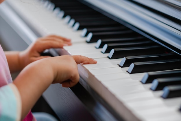 Mains de petite fille jouant du piano mise au point sélective