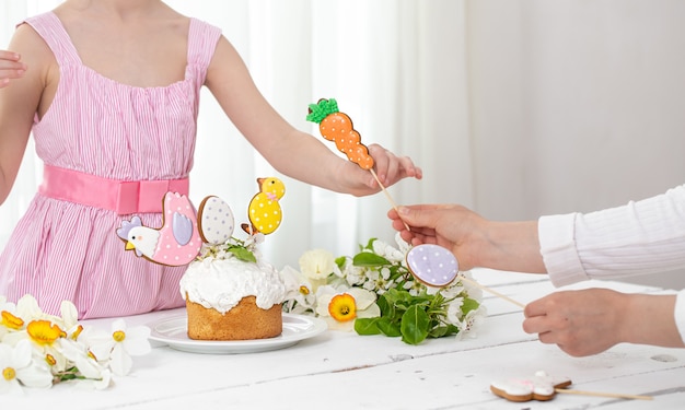 Mains d'une petite fille et mère en train de décorer un gâteau de fête.