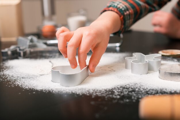 Les mains des petites filles jouent avec des formes de coupe pour les biscuits en pain d'épice.