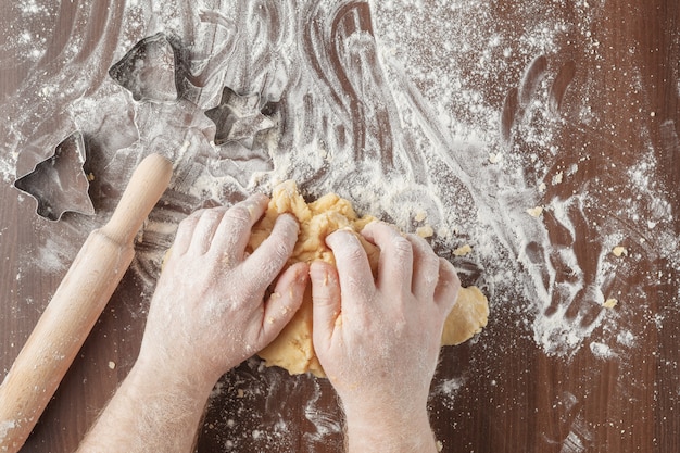 Mains, pétrir la pâte sur une table en bois marron