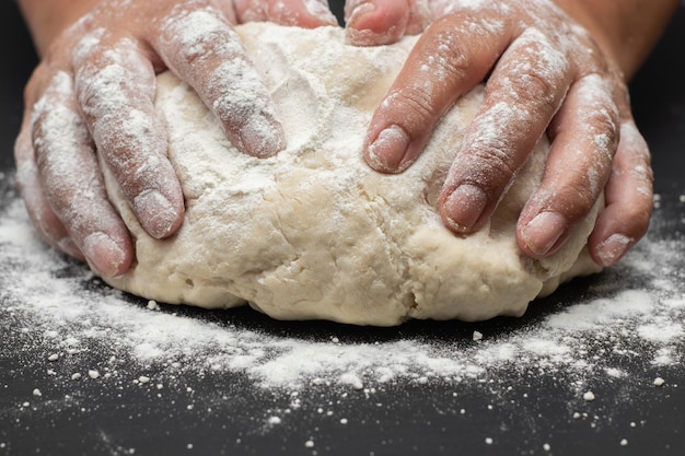 Mains pétrissant la pâte à pain sur le tableau noir