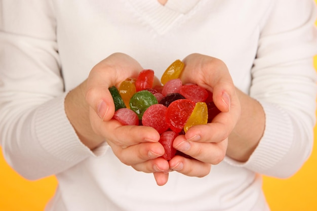 Mains pleines de bonbons sur fond jaune