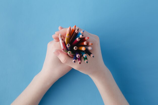 Des mains pleines de crayons de couleur