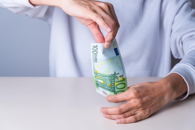 Mains pliant un billet de cent euros