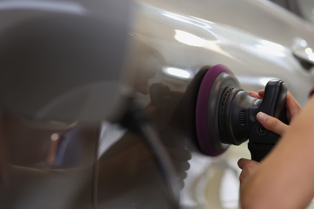 Mains avec polisseuse orbitale dans un magasin de voitures polissant les rayures sur un concept de voiture