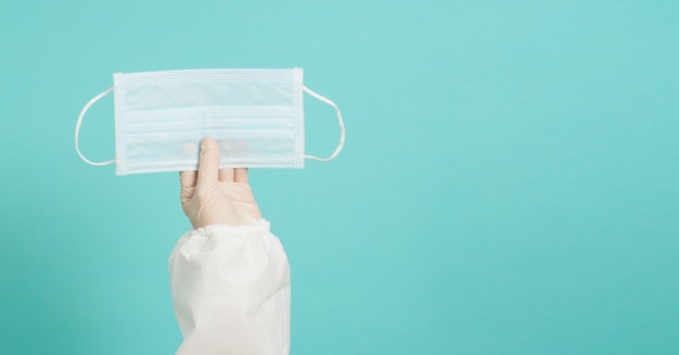 Les mains portent un EPI blanc avec des gants médicaux et un masque facial. Mettez sur fond vert ou bleu Tiffany.