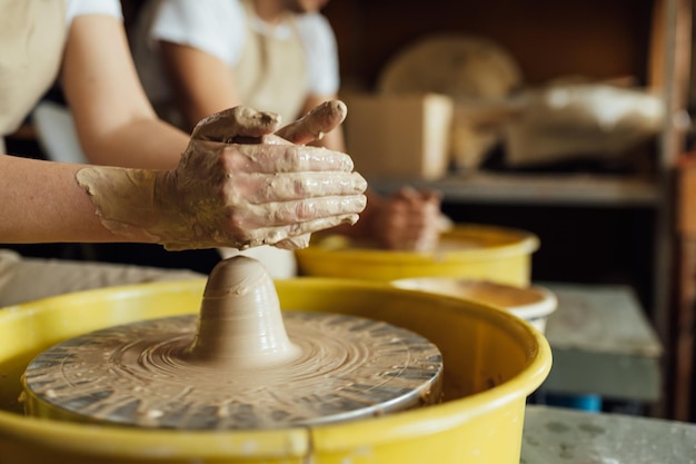Mains d'un potier fabriquant un pot en céramique sur le tour de potier
