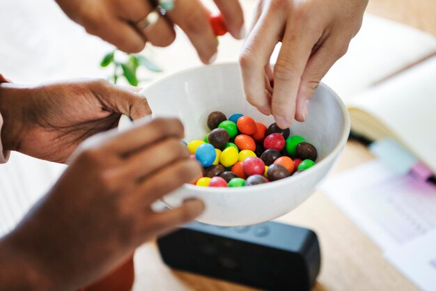 Mains prenant des bonbons sucrés dans une tasse