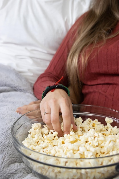 mains prenant du pop-corn dans un bol