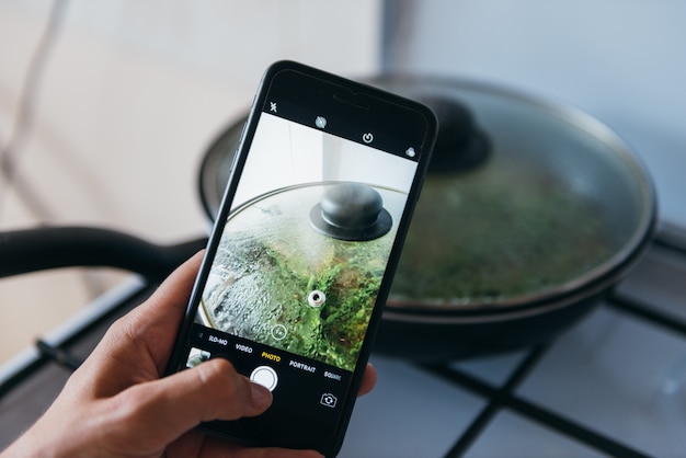 Mains prenant une photo de pan avec des verts avec smartphone