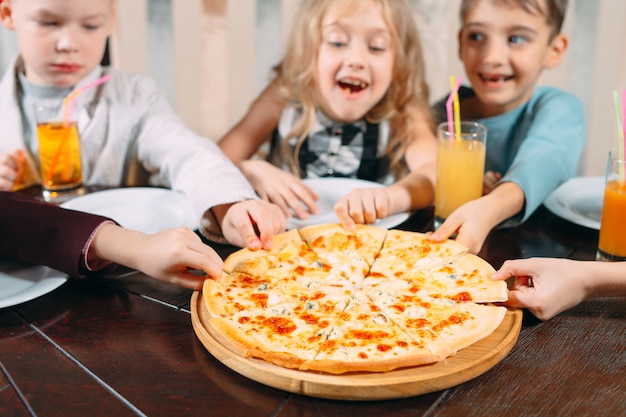 Mains prenant des tranches de pizza de la table en bois, bouchent la vue.