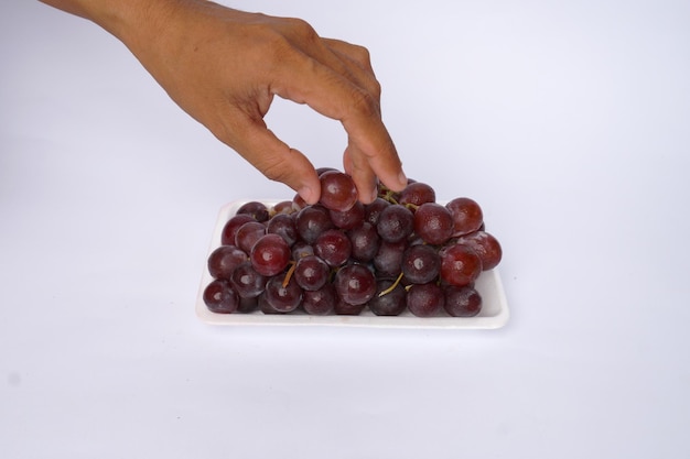 Les mains prennent des raisins isolés sur fond blanc