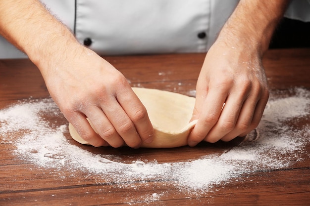 Mains préparant la pâte à base de pizza sur la table en bois libre