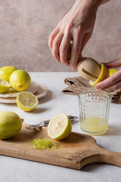 Mains pressant du citron et des citrons sur une planche à découper en bois