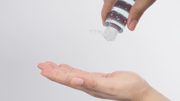 Les mains pressent le gel pour les mains à l'alcool sur fond blanc.