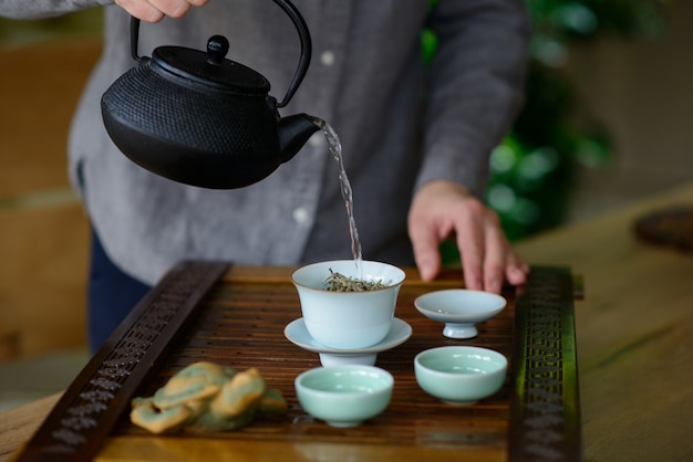 Les mains professionnelles d'un maître de thé cuisinent montrent une cérémonie du thé. Ensemble de cérémonie du thé. Thé blanc chinois.