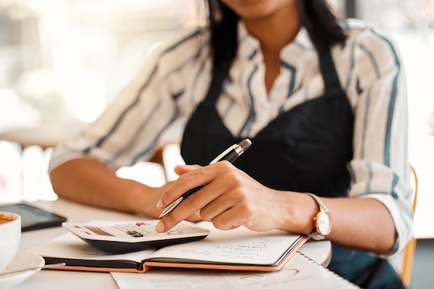 Mains d'un propriétaire d'entreprise prenant des commandes calculant les bénéfices et travaillant sur le budget pour le démarrage tout en étant assis à une table au travail