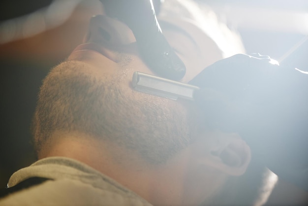 Les mains rasent le plan rapproché de rasoir de barbier d'hommes de barbe