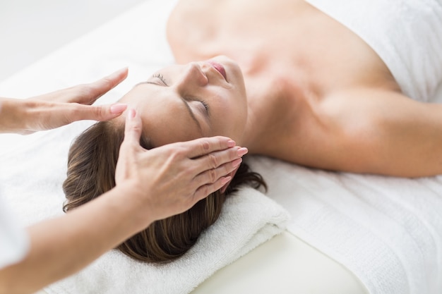 Mains recadrées de thérapeute effectuant un reiki sur une femme