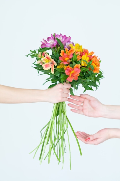 mains remettant un bouquet d'alstroémères de fleurs