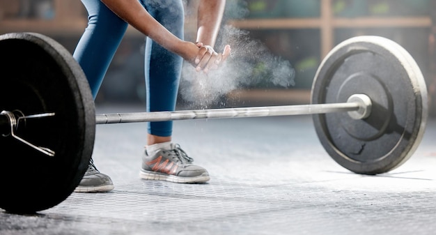 Mains de remise en forme ou bodybuilder avec de la poudre ou des haltères dans l'entraînement ou l'exercice pour les objectifs corporels Deadlift personne en bonne santé ou athlète sportif haltérophilie avec de la poussière de craie dans un studio de club de gym