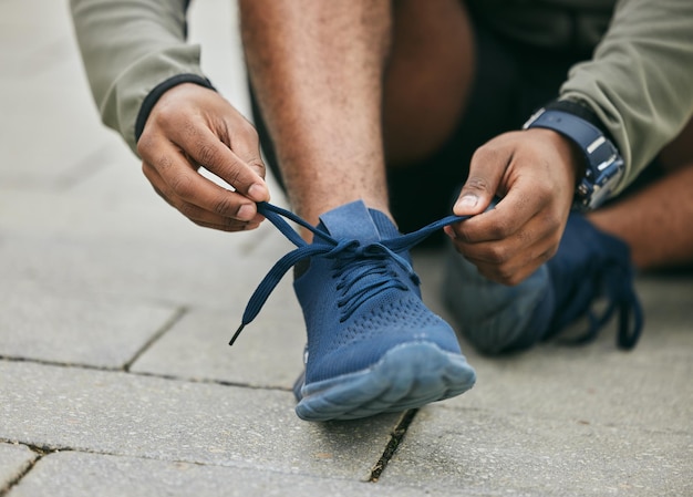 Photo les mains de remise en forme et l'homme noir nouent des chaussures en ville et se préparent à courir l'entraînement ou l'exercice