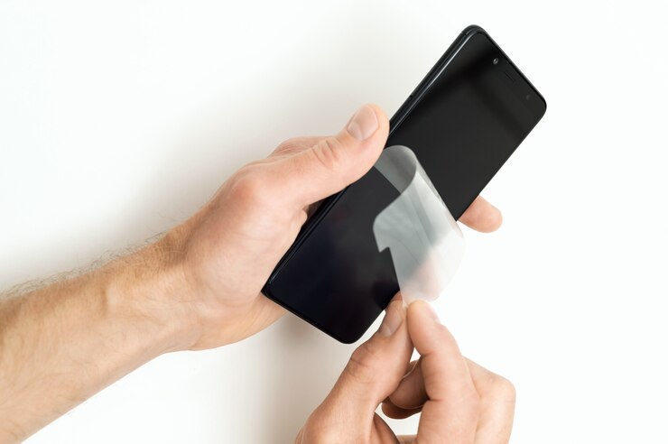 Mains retirant le film protecteur de l'écran du smartphone