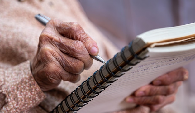 mains ridées pour une personne âgée écrivant des notes sur son carnet de notes
