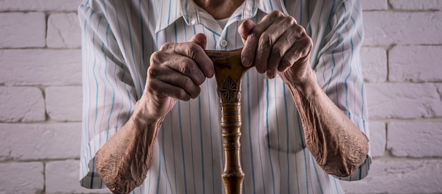 mains ridées d'un vieil homme avec une béquille