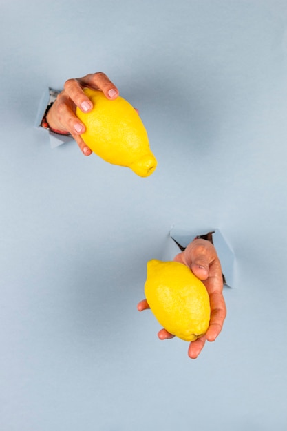 Mains saisissant d'un trou à fond bleu avec deux citrons