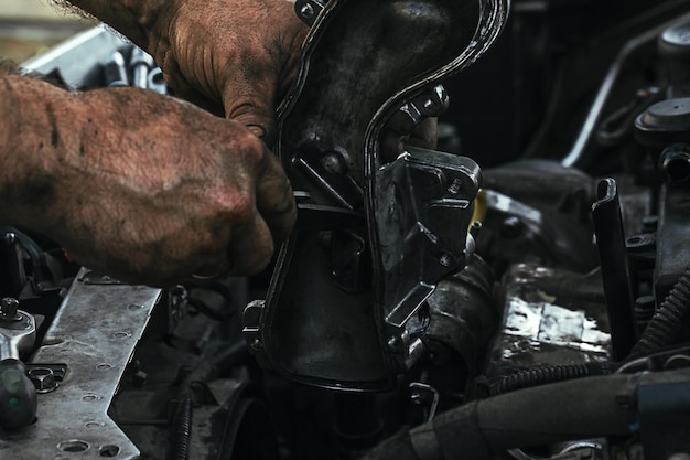 Les mains sales et graisseuses d'un homme réparant le moteur, la vanne EGR dans la voiture se bouchent.