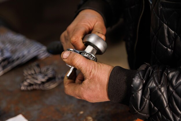 Mains sales d'un technicien automobile caucasien tenant une clé à filtre à huile réglable argentée en gros plan avec mise au point sélective