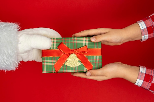 Les mains de Santa39s donnent des cadeaux aux enfants sur fond rouge de Noël