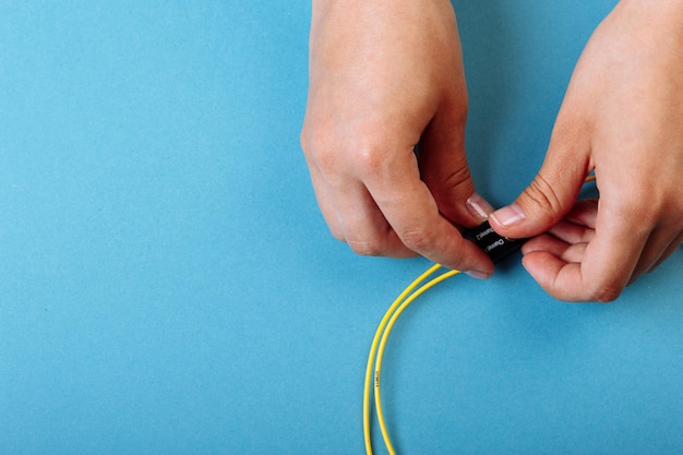 Les mains se préparent à régler un atténuateur optique variable avec un tournevis Fond bleu