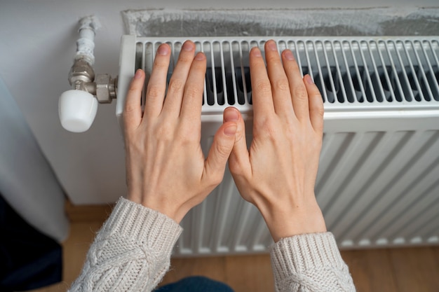 Les mains se réchauffent sur le radiateur en gros plan