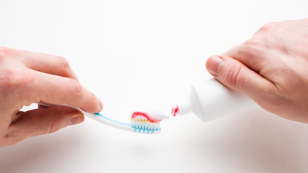 Photo mains serrant le dentifrice sur la brosse