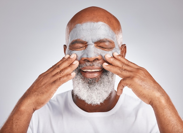 Mains de soins de la peau ou vieil homme avec crème pour le visage marketing ou publicité produit de beauté de luxe pour les soins personnels Cosmétiques de fond de studio ou homme noir âgé avec un sourire heureux appliquant un masque facial