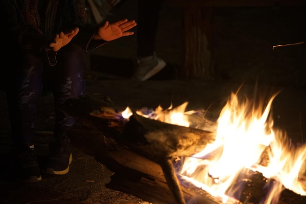 Les mains sont au-dessus d'un feu de joie dans un feu de camp