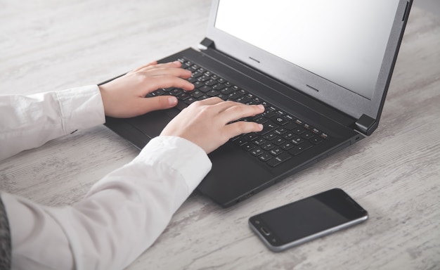 Mains tapant sur le clavier d'ordinateur portable au bureau.