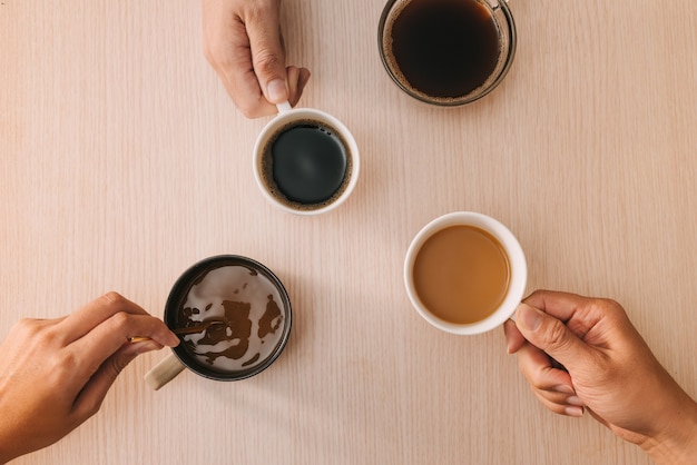 Mains avec des tasses de café sur la surface en bois