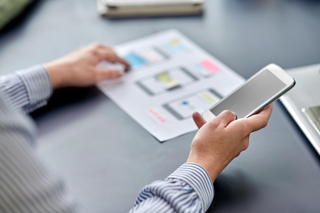 avec les mains sur le téléphone travaillant sur la conception de l'UI au bureau