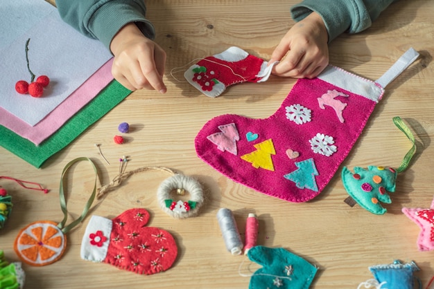 Mains tenant l'aiguille et la couture chaussette de Noël en feutre pour la décoration de Noël et du nouvel an