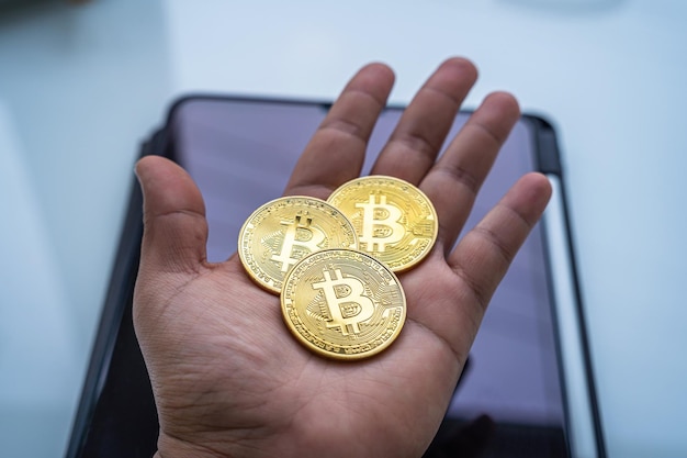 Mains tenant des bitcoins dorés ou des pièces de crypto-monnaie ou des symboles sur une tablette numérique dans un tableau blanc Concept de monnaie future