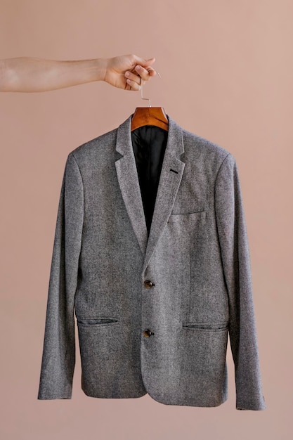 Mains tenant un blazer gris dans un cintre