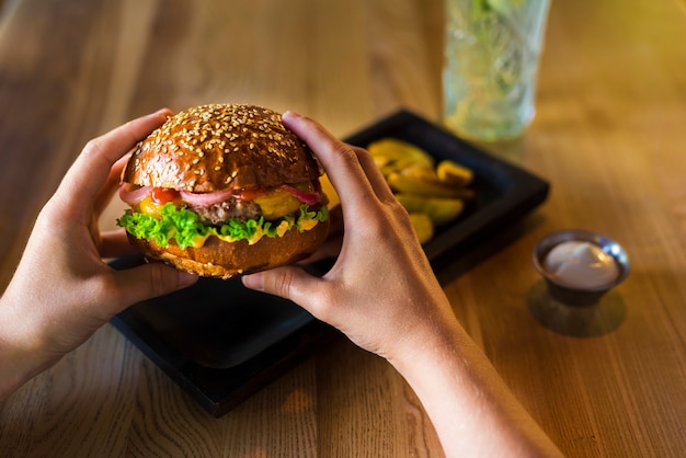 Photo mains tenant un burger de bœuf savoureux avec de la laitue