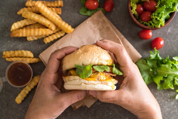 Mains tenant un burger savoureux avec frites et sauce