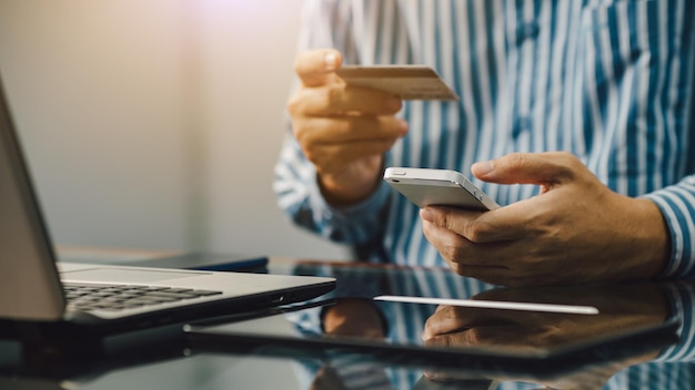 Mains tenant une carte de crédit pour les achats en ligne et les services bancaires par Internet pour les transactions financières