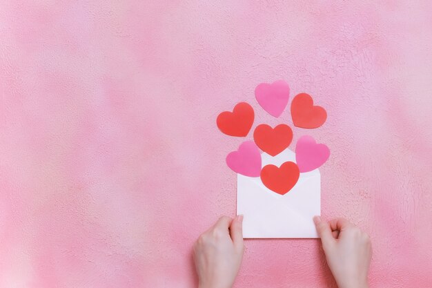 Mains tenant une enveloppe avec des coeurs en papier, concept de la Saint-Valentin